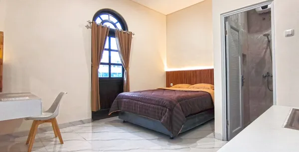 Esquina del dormitorio de AVILITA House con ventana de luz natural y cortinas blackout para descansar